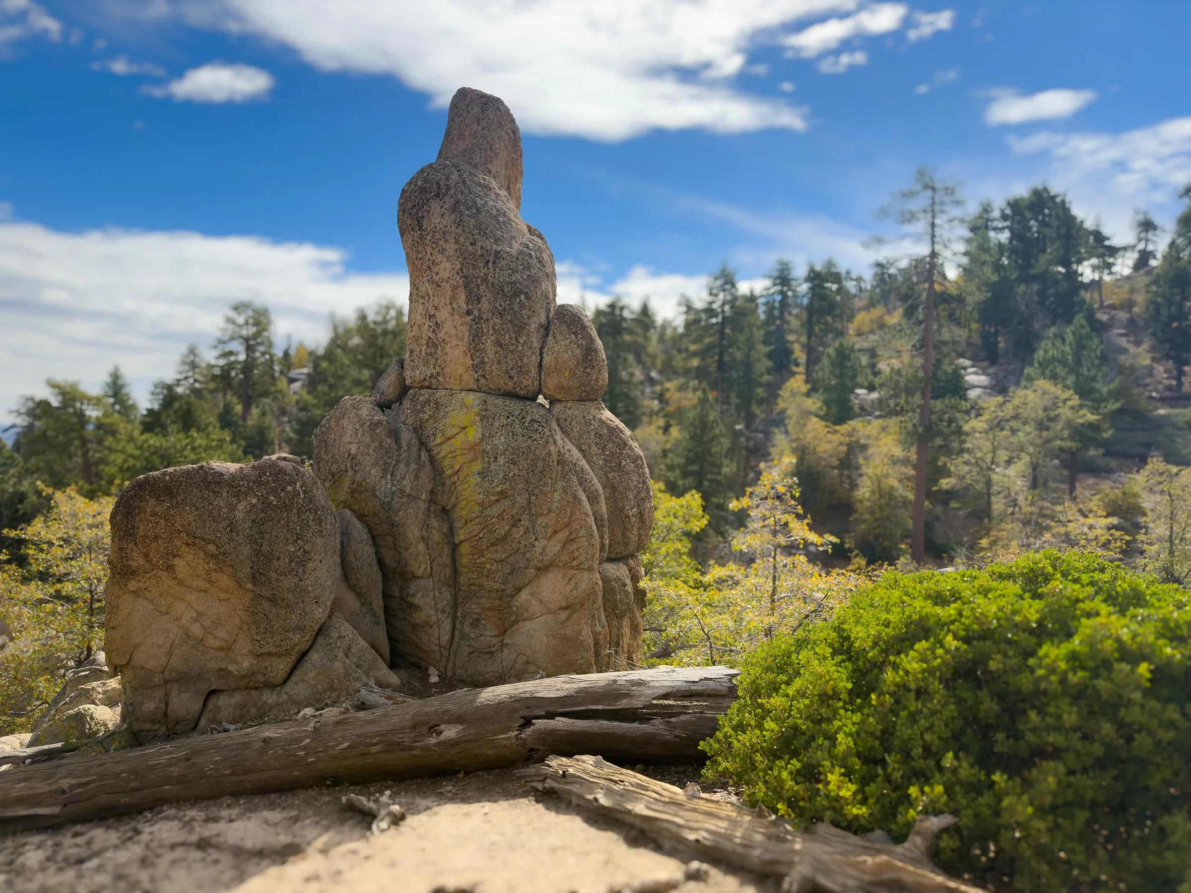 A tall stacked granite tower with a weathered log at its base